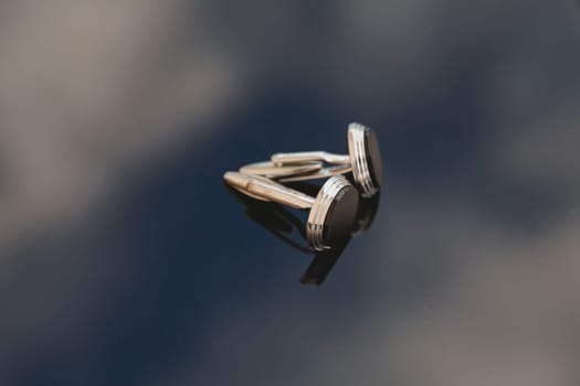 A pair of men's cufflinks on a mirror background. Close-up. Selective focus.