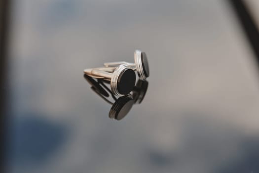 A pair of men's cufflinks on a mirror background. Close-up. Selective focus.