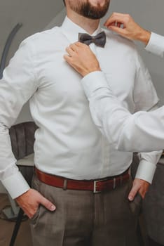 Man fixing his bow tie. Man groom in wedding suit with a bow tie. Close-up.