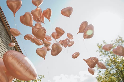 Heart-shaped balloons take off into the sky. Soft focus.