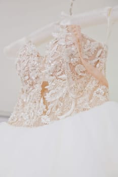 The delicate bride's dress is hanging in room. Selective focus. Close-up.