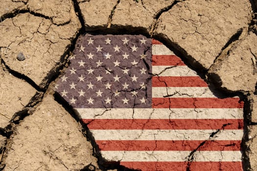 Ecological concept. Drought. On dry, cracked ground, an image of the US flag.