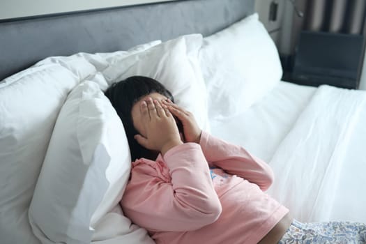 a upset child girl cover her face with hand .