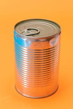 Unopened Tin Can with Blank Edge on Orange Background. Canned Food. Aluminum Can for Safe and Long Term Storage of Food. Steel Sealed Food Storage Container