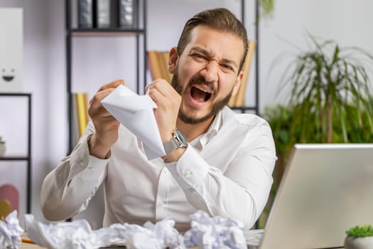 Angry furious businessman working at office throwing crumpled paper, having nervous breakdown at work, migaine, headache, stress management, mental distress problems, losing temper reaction on failure