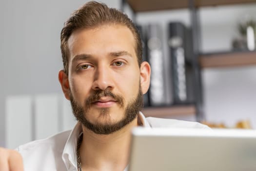 Close-up portrait bearded businessman face freelancer at home office workplace working on laptop computer. Manager freelancer middle eastern man works on notebook send messages makes online purchases