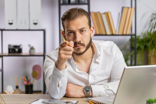 I choose you. Middle eastern businessman programmer software developer working on office laptop pointing to camera, looking with happy expression, making choice, showing direction. Arab freelancer man