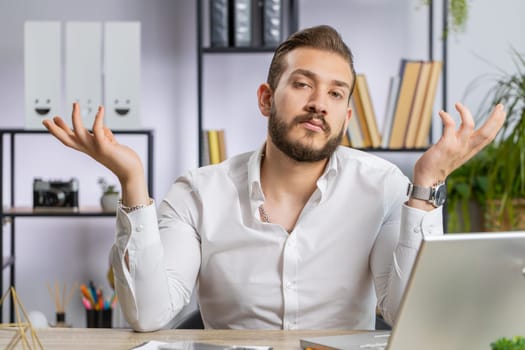 I dont know what to say. Confused business man working on laptop at office workplace. Freelancer feeling embarrassed about ambiguous question, having doubts, no answer idea, being clueless, uncertain