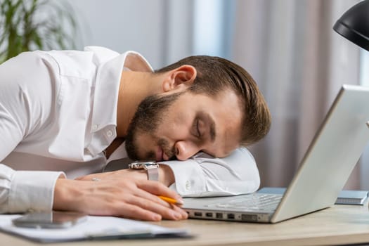 Bored sleepy middle eastern businessman worker working on laptop computer, leaning on hand falling asleep at office. Exhausted tired freelancer workaholic lebanese man. Employment, occupation workless
