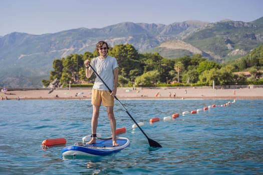 Young men Having Fun Stand Up Paddling in blue water sea near st stefan island in Montenegro. SUP.