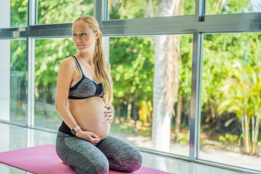 Young pregnant woman doing yoga exercises and meditating at home or yoga studio. Health care, mindfulness, relaxation and wellness concept.
