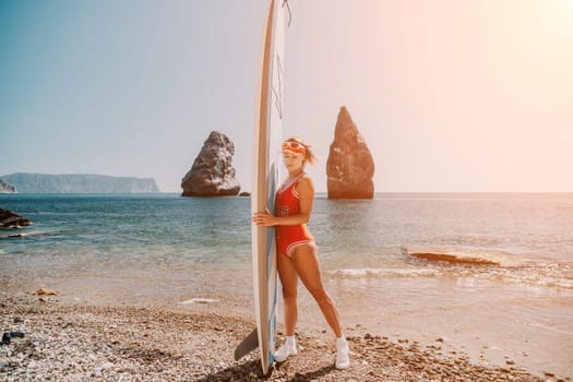 Close up shot of beautiful young caucasian woman with black hair and freckles looking at camera and smiling. Cute woman portrait in a pink bikini posing on a volcanic rock high above the sea