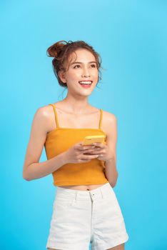 Portrait of an excited young girl in summer clothes holding mobile phone