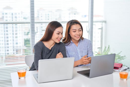 business, teamwork and people concept - female team or businesswomen with laptop computer working at office