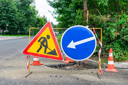 Road signs indicating the repair of asphalt and the direction to bypass the dangerous section