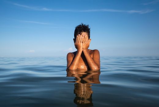 Relaxation and healthy lifestyle. Young boy teenager bathes in the sea.