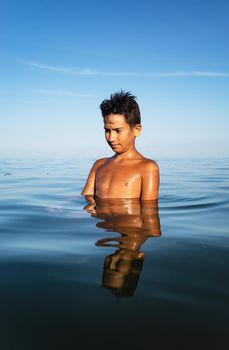 Relaxation and healthy lifestyle. Young boy teenager bathes in the sea.