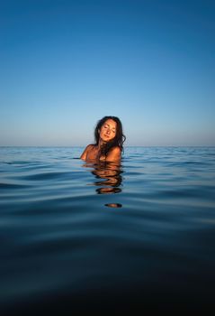 Relaxation and healthy lifestyle. Young beautiful and emotional woman swims in the sea on a sunny day. Portrait in sea water