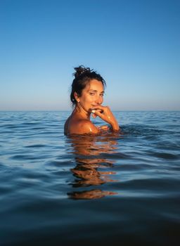 Relaxation and healthy lifestyle. Young beautiful and emotional woman swims in the sea on a sunny day. Portrait in sea water