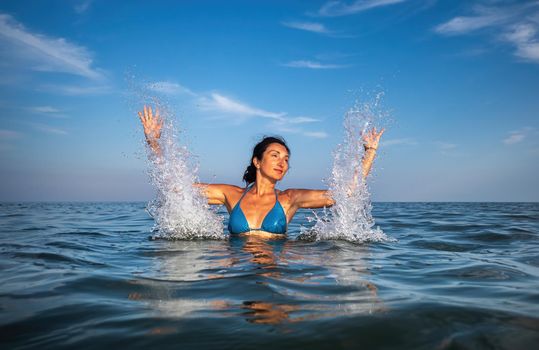 Relaxation and healthy lifestyle. Young beautiful and emotional woman swims in the sea on a sunny day