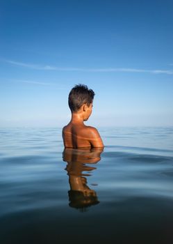 Relaxation and healthy lifestyle. Young boy teenager bathes in the sea.