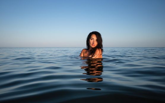 Relaxation and healthy lifestyle. Young beautiful and emotional woman swims in the sea on a sunny day. Portrait in sea water
