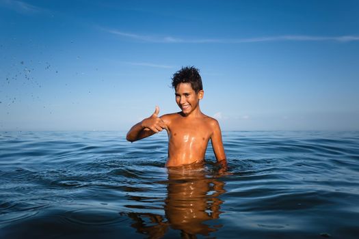 Relaxation and healthy lifestyle. Young boy teenager bathes in the sea.