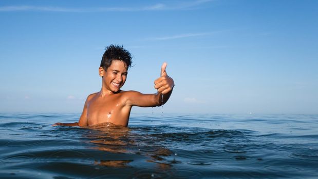 Relaxation and healthy lifestyle. Young boy teenager bathes in the sea.