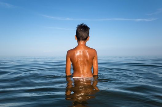 Relaxation and healthy lifestyle. Young boy teenager bathes in the sea.