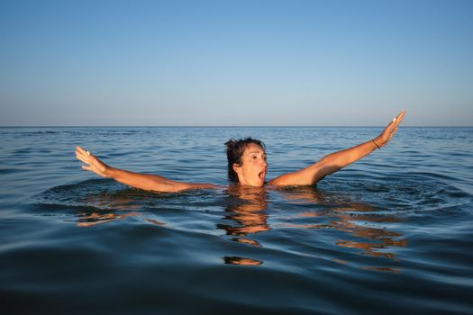 Relaxation and healthy lifestyle. Young beautiful and emotional woman swims in the sea on a sunny day