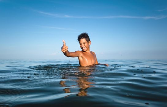 Relaxation and healthy lifestyle. Young boy teenager bathes in the sea.