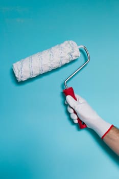 Image of man holding paint roller in front of blue wall.