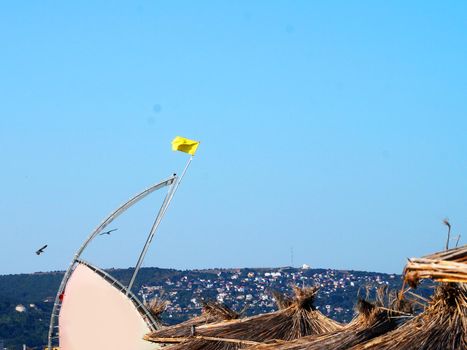 yellow warning flag on a rescue tower on the sea beach.