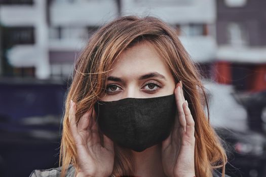 Portrait of anxious teenage girl wearing protective face medical mask standing on city street