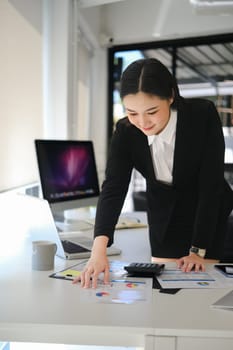 Professional businesswoman analyzing sales statistics document at office desk.