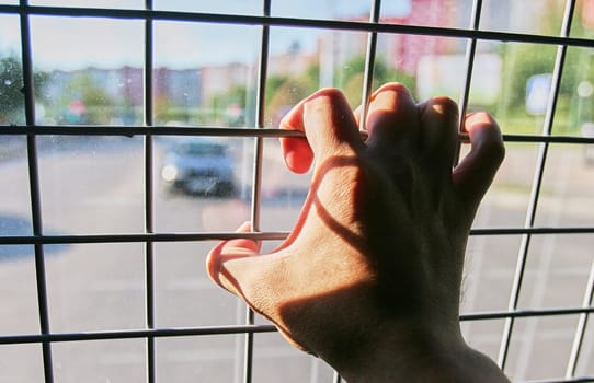 Man in prison hand holding a steel cage prison bars. criminal criminal is locked in prison. The hand of a detained man in a police car.