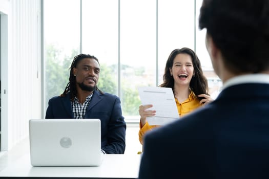 Job interview concept. Diverse hr team doing job interview with a man in business office. Happy business people working in office. Hiring and recruitment concept. Positive business office meeting. 