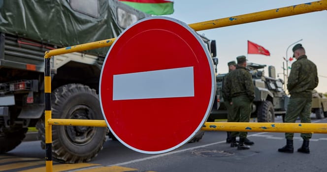 Soldiers stand near the car against the background of the STOP sign. The Belarusian military is conducting exercises.