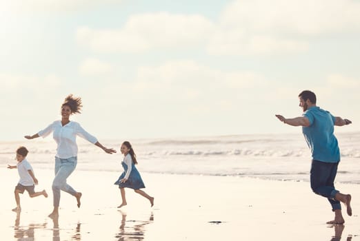 Mother, father and children on the beach to dance together while outdoor for travel or vacation in summer. Sunset, family or children and siblings having fun with parents on the coast by the ocean.