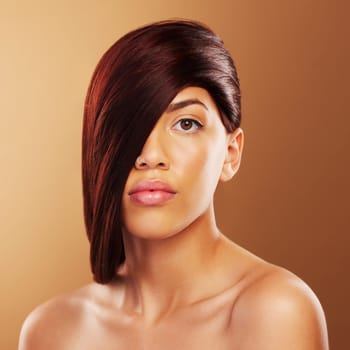 Hair care, portrait and a young woman in studio for salon, hairdresser and wellness results. Beauty, cosmetics and shampoo for growth and shine of a serious model person on a brown background.