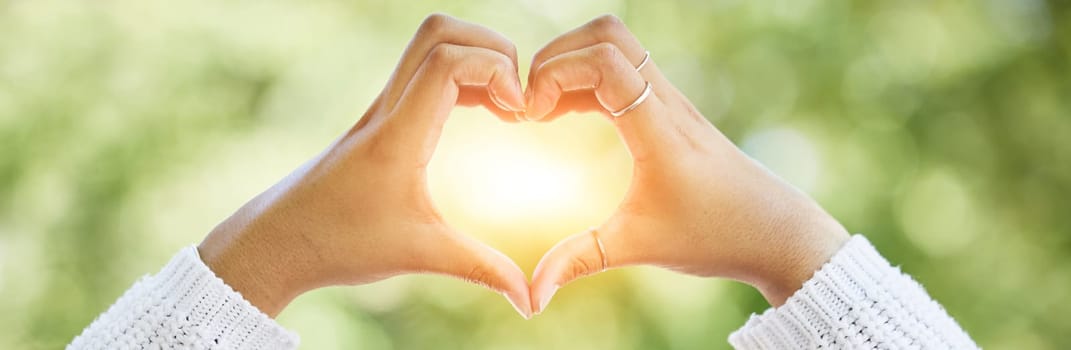 Love, heart and lens flare with hands of woman in nature for support, motivation and kindness. Thank you, peace and hope with closeup of person and sign in outdoors for emoji, health and banner.