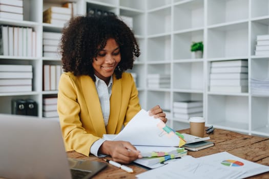 financial, Planning, Marketing and Accounting, portrait of african american employee checking financial statements using documents and calculators at work.