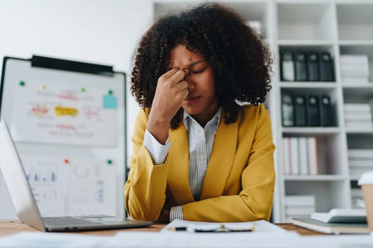 Burnout American African business woman in stress works with many paperwork document, migraine attack, Freelance, work at office.