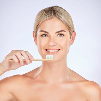 Portrait, woman and brushing teeth in studio for healthy dental wellness on background. Face of female model, bamboo toothbrush and cleaning mouth for fresh breath, oral hygiene and care for smile.