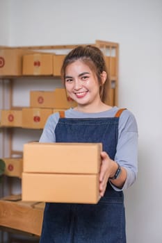 Online business concept, Asian business women holds parcel boxes of product for delivery to client.