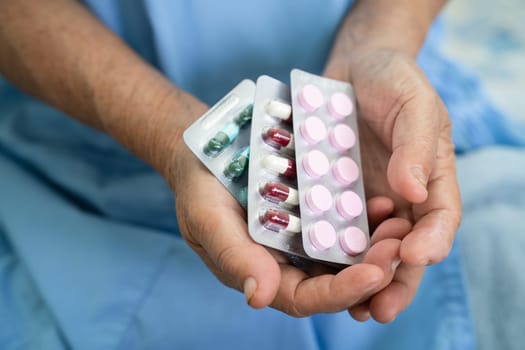 Asian elderly woman patient holding drug in her hand, healthy strong medical concept.