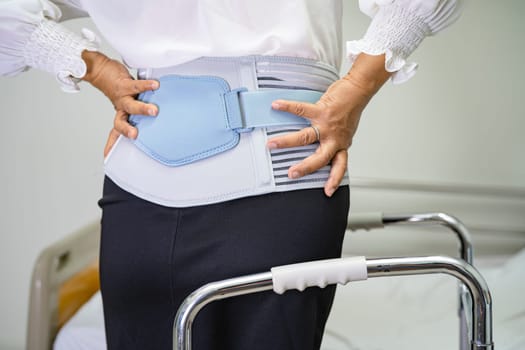 Asian lady patient wearing back pain support belt for orthopedic lumbar with walker.