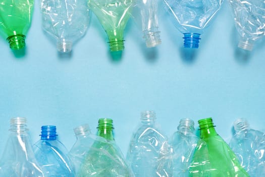 Flat plastic bottle recycling design blue paper. Row empty bottle PET plastic recycling concept. Flat crushed bottle crumpled plastic garbage PET recycling background trash. Reuse. Used. Waste sorting