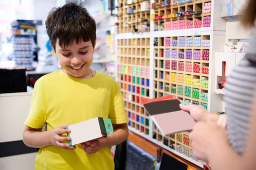 Handsome Caucasian teen schoolboy smiles broadly, enjoying shopping in stationery store. Office supply shop. Creative people. Hobby. Fine art. Education. Preparations for the start of new school year