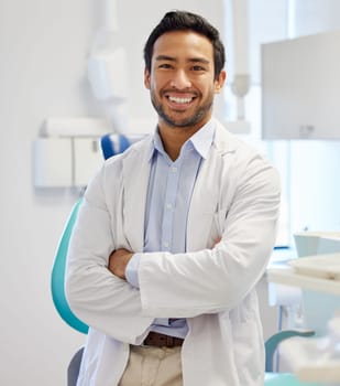 Dentist, portrait and man with arms crossed for healthcare service, dental hospital or insurance in consultation office. Happy asian person or doctor with teeth, oral or hygiene health in clinic.